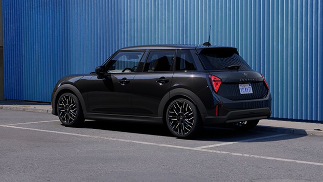 Frontal view of a parking MINI Cooper 5-Door in Icy Sunshine Blue and Multitone Blue Roof on street with orange wall in the background